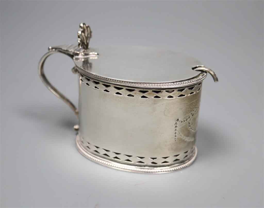 A George III pierced silver oval mustard pot, maker, W?, London, 1785, with blue glass liner and associated plated spoon.